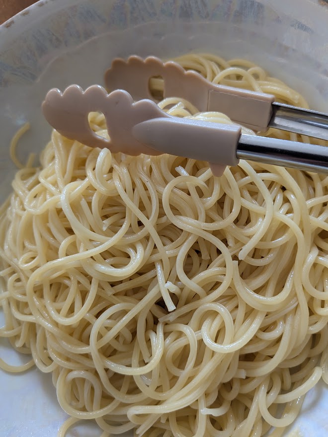 取り分け用のトングを添えたパスタ