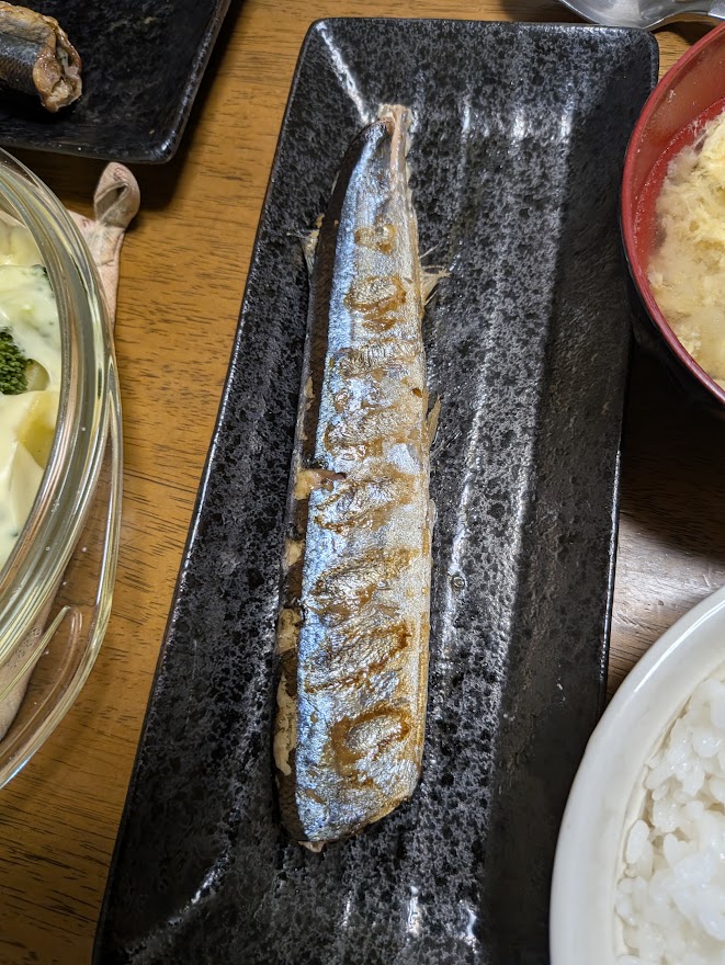 黒い皿に盛られた焼き魚
